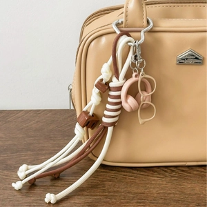 Handmade khaki rope bag charm with mini headphone and glasses accessories on a leather tote
