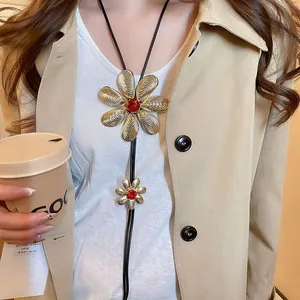 Detail of gold floral bolo tie necklace with red gems on casual outfit context