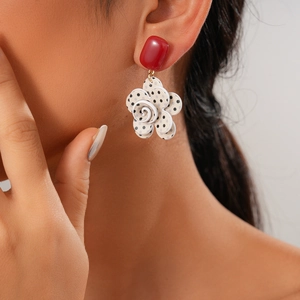Close-up of vintage flower drop earring with red rectangle stud and black polka dot petals
