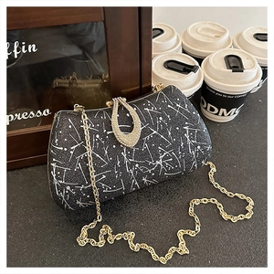 Detail of evening bag with white splatter pattern, diamond teardrop clasp and gold chain