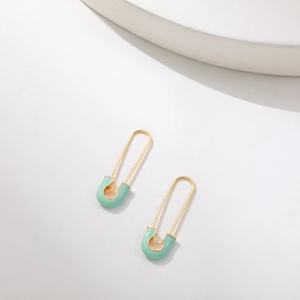 Detail of safety pin earrings in gold finish with mint green enamel coating