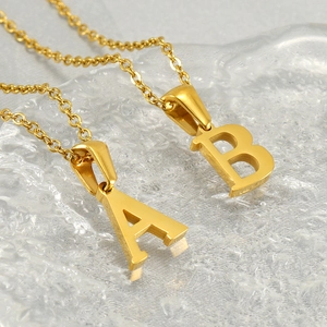 Colliers en acier doré avec pendentifs lettres A et B sur texture de glace en cristal