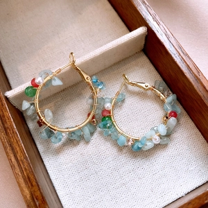 Detailed shot of golden hoop earrings with colorful stones and pearls in a wooden box