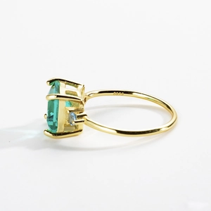 Macro side view of S925 silver ring with emerald cut green stone and blue crystals