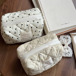 Quilted corduroy pouches with heart and floral patterns on a rustic wooden desk