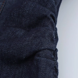 Gedetailleerde macro-opname van donkerblauwe denimtextuur en precieze naden op de jurk