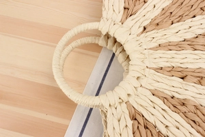 Close-up of a circular woven paper rope handbag with round handles and mixed textures