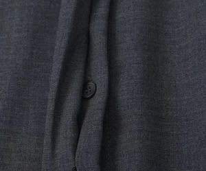 Vue macro du tissu tissé gris anthracite avec fermeture par un bouton rond assorti