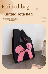 Close-up of black knit wrist bag featuring a pink bow pattern and large capacity