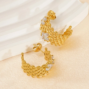 Detail of gold C-shaped earrings with woven bead texture and inlaid square crystals
