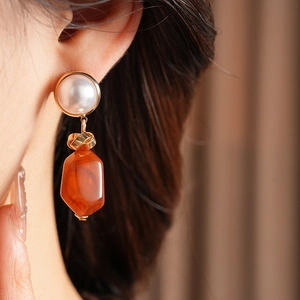 Detailed view of irregular resin pearl earrings on a model with warm amber tones