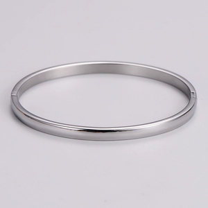 Detail view of oval silver metal bracelet showing side hinge clasp and polished finish