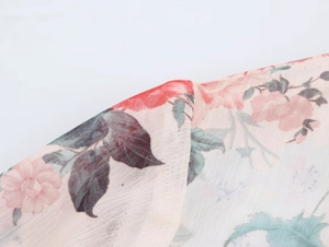 Macro detail of lightweight floral chiffon fabric with pink blooms and dark leaves