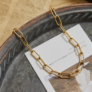 Minimalist gold paperclip chain necklace displayed elegantly on a vintage textured plate