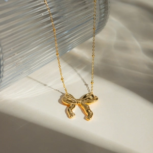 Close-up of 18k gold-plated stainless steel bow necklace with delicate beaded chain