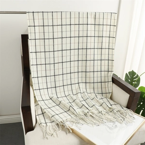 Classic beige plaid scarf with black grid patterns and fringe tassels on a wooden chair