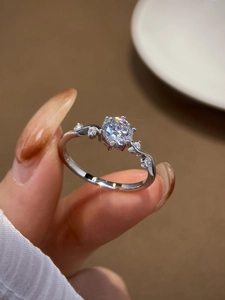Macro shot of a classic six-prong silver ring featuring a round cut sparkling moissanite stone