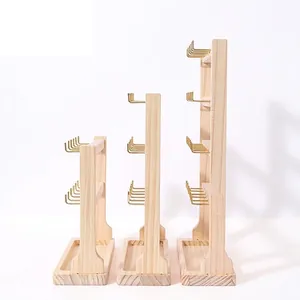 Three-piece wooden jewelry display stands with gold hooks and tray bases on white background