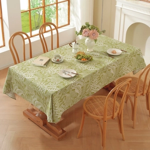 Close-up of green cotton linen tablecloth with white leaf pattern on a wooden table
