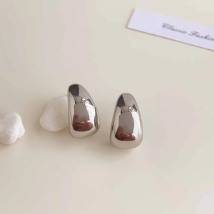 Polished silver irregular water drop earrings on a minimalist cream background display
