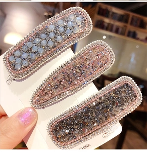 Macro detail of three-piece crystal hair clips with faux pearls on white card