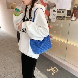 Détail d'un sac à bandoulière en velours côtelé bleu montrant la texture sur un modèle