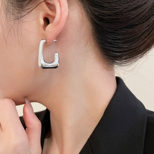 Close-up of a silver-tone U-shaped geometric earring worn by a model in profile