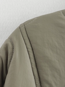 Macro view of double stitching and windproof quilted fabric detail on khaki jacket