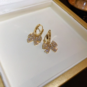 Close-up of gold-plated bow earrings with sparkling cubic zirconia in a jewelry box
