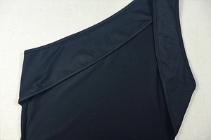 Dettaglio dell'abito nero monospalla che mostra il tessuto elastico e le cuciture precise