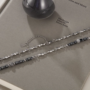 Detail of titanium steel necklace featuring black square beads and gray marbled beads