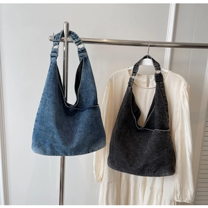Detail of blue and black denim tote bags with metal ring connectors on a minimal rack