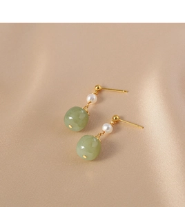 Detail of vintage freshwater pearl and green jade drop earrings on champagne silk background
