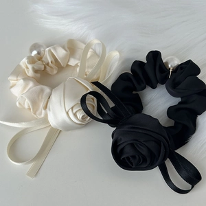 Elegant satin rose hair scrunchie with ribbons and pearl detail on white faux fur background