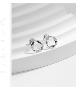 Macro detail of twisted S925 silver wave earrings with a polished metallic finish