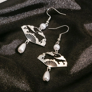 Detail of silver fan-shaped hollow earrings with white pearls on a black background