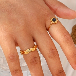 Detail of 18K gold plated wavy ring and sunburst ring with blue gemstone on model