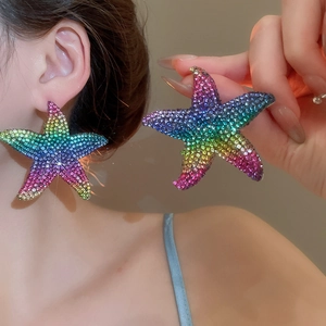 Detail of colorful rainbow rhinestone starfish earrings held to show large size and shine