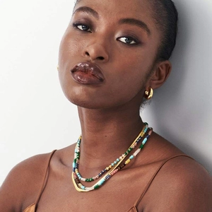 Detailed close-up of layered colorful beaded necklace and elegant gold flat snake chain