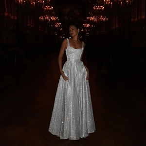 Détail d'une robe de soirée à paillettes argentées dans une salle de bal luxueuse