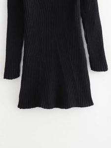 Close-up of black ribbed knit fabric showing the texture and hem of the slim-fit dress