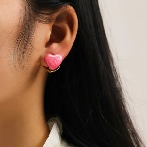 Gros plan de boucles d'oreilles cœur rose marbré avec base dorée sur un mannequin