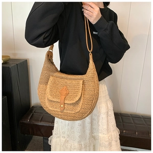 Detail of hand-woven straw shoulder bag with brown leather strap and buckle pocket