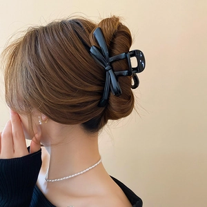 Elegant glossy black bow hair claw clip for high bun hairstyle on a woman back view