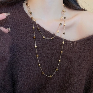 Detail of 18k gold plated necklace with tiger eye beads and pearls on brown sweater