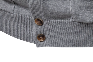 Detail of grey knitted cardigan showing ribbed hem and textured brown buttons