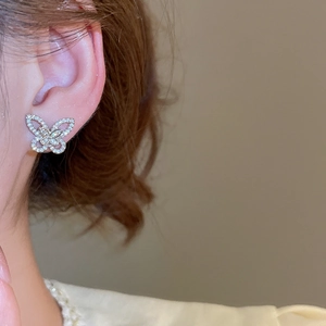 Close-up of sparkling hollow butterfly stud earring with zircons on model ear
