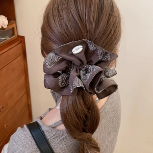 Detailed close-up of dark brown paisley print scrunchie with white resin button detail