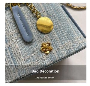 Detail of light blue tweed bag featuring gold camellia rivet and textured chain buckle