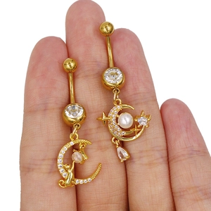 Detail von goldenen Bauchnabelpiercings mit Mond-, Katzen- und Sternenanhängern und Zirkon